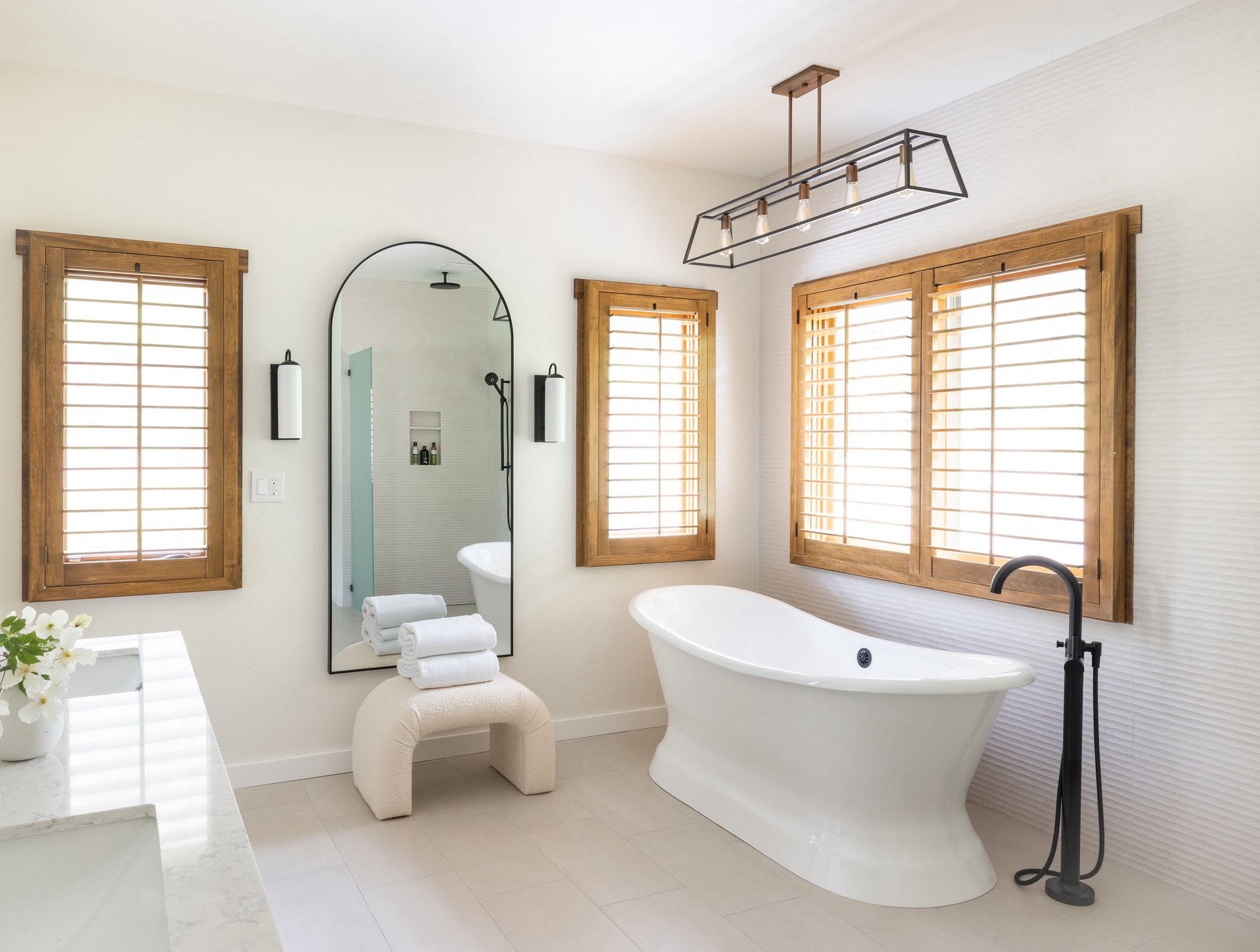 Bright bathroom with freestanding tub and natural wood shutters